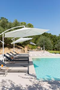 Una piscina con sillas y una sombrilla blanca al lado de una piscina. en Villa Sweetest Wish, en Bevagna