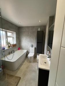 a bathroom with a tub and a toilet and a sink at Luxurious Shared Home - Self Check-In, Free Street Parking in Leavesden Green