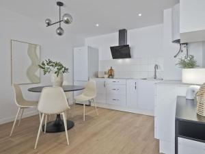 a white kitchen with a table and chairs at Estudio Temporal a 2' de la playa de Sagunto A2 in Puerto de Sagunto