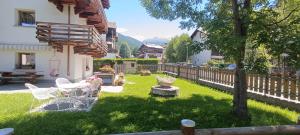 einen Garten mit einem Zaun, einem Tisch und Stühlen in der Unterkunft Appartamento TEMELIN in Bormio