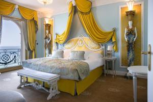 a bedroom with a king sized bed with yellow curtains at Hotel Le Negresco in Nice