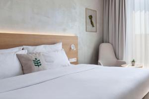 a bedroom with a white bed and a chair at Botanique Hotel Prague in Prague
