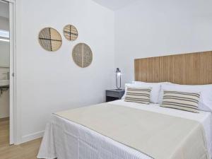 a white bedroom with a bed with two mirrors on the wall at Refugio Costero a 2 minutos de Playa Sagunto A4 in Puerto de Sagunto