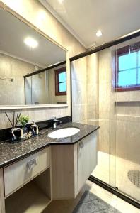 a bathroom with a sink and a mirror and a shower at 3 dormitórios ao lado da Rua Coberta in Gramado +34 photos