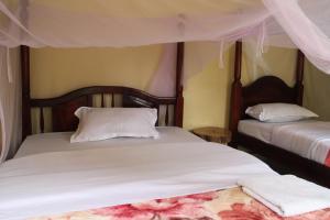 a bedroom with two beds with white sheets at Kibale Eco-Home in Bigodi
