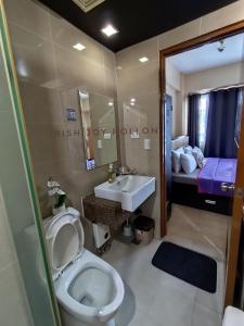 a bathroom with a toilet and a sink and a bed at Condotel Near Naia Terminal 3 in Manila