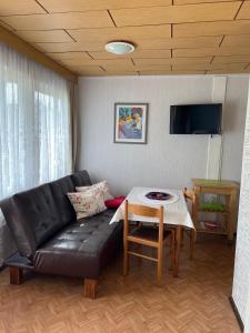 ein Wohnzimmer mit einer schwarzen Ledercouch und einem Tisch in der Unterkunft Ferien-Bungalow -2- im Seebad UeckermündeOT Bellin in Ueckermünde