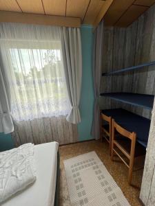 ein kleines Schlafzimmer mit einem Bett und einem Fenster in der Unterkunft Ferien-Bungalow -2- im Seebad UeckermündeOT Bellin in Ueckermünde + 6 Fotos