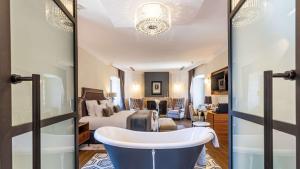 a bathroom with a bath tub and a bedroom at Domaine de Dolomieu Hotel & Spa - BW Premier Collection in Dolomieux
