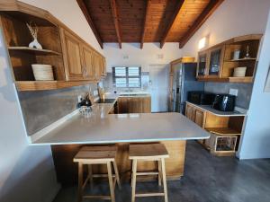 a kitchen with a counter and two stools in it at UMDLOTI House - Upper private level- Beach Road - LOCATION in Umdloti +15 photos