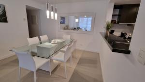 a dining room with a glass table and white chairs at Nancy Forest 888 in Punta del Este