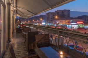 un restaurante con mesas y sillas en un balcón por la noche en Sultan Modern Hotel, en Skopje