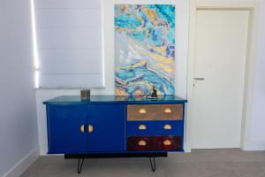 a blue dresser in a room with a painting at Penthouse Cathedral and Seaview Terrace V2 in Valletta