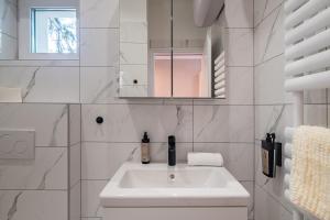 a white bathroom with a sink and a mirror at Balatonic Moon&Sun apartmanház in Siófok +62 photos