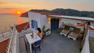 una mujer sentada en una mesa en un balcón viendo la puesta de sol en Peppermint Bay, en Skopelos Town