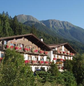ein Gebäude mit Blumen auf den Balkonen mit Bergen im Hintergrund in der Unterkunft Ferienland Stubai in Fulpmes