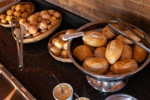Ein Stapel Brötchen und Schüsseln mit Brot auf einer Theke in der Unterkunft Canyons Camping Capitolio in Capitólio