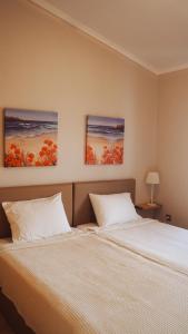1 Schlafzimmer mit 2 Betten und 2 Gemälden an der Wand in der Unterkunft Summer house in Halkidiki in Paralia Dionisiou