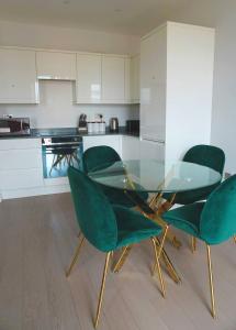 Una mesa de cristal y cuatro sillas verdes en una cocina. en Luxury Flat 1 Bedroom Flat I Working Professionals & Contractors I Flat 86, en Saint Albans