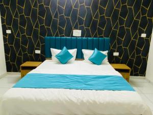 een slaapkamer met een blauw en wit bed met blauwe kussens bij Hotel Balaji Villa in Vadodara +3 foto's
