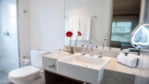 a bathroom with a sink and a toilet and a mirror at Quality Porto Alegre in Porto Alegre
