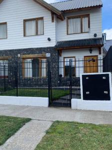 una casa con una valla negra delante en Duplex con Excelente ubicación, en Esquel