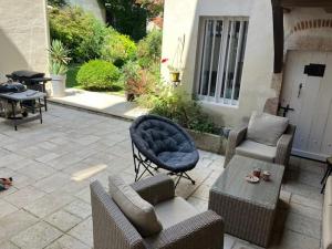 a patio with chairs and a couch and a table at Les Pampilles in Saint-Jean-de-Losne