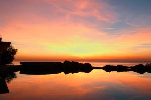 a reflection of a sunset in a body of water at Hotel Villa Margherita in Quercianella