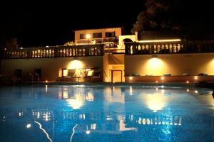a large swimming pool in front of a building at night at Hotel Villa Margherita in Quercianella