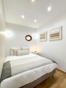 a white bedroom with a bed and a clock on the wall at Villa Des Bégonias - PSG in Le Pré-Saint-Gervais