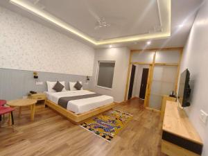 a bedroom with a bed and a table and a television at The Clove Ladakh in Leh