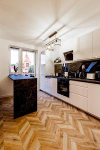 a kitchen with white cabinets and a black counter top at Feels like home Apartment - Olsztyn in Olsztyn