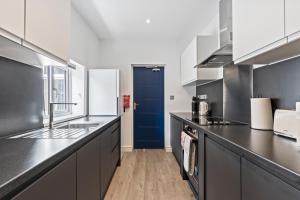 a kitchen with black counters and a blue door at 4 Beds 3 Bath (2-ensuites) Free Parking 75Mbps in Stoke on Trent