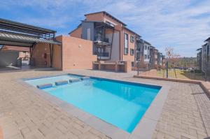 a large blue swimming pool in front of a building at Mkhonto's waterfall ridge in Midrand
