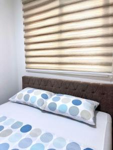 a bed with a pillow and a window with blinds at Apartman T&A in Trebinje
