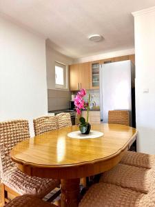 a kitchen with a wooden table with a vase of flowers on it at Apartman T&A in Trebinje