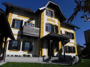 a yellow and white house with a balcony at Vila Mila in Bled