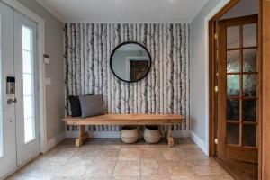 ein Spiegel an einer Wand mit einer Bank im Flur in der Unterkunft Eko Eau Bonheur in Saint Adolphe D'Howard