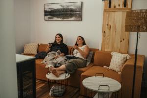 two women sitting on a couch in a living room at Kartalla - the A frame experience in Tremblant in Saint-Rémi-dʼAmherst