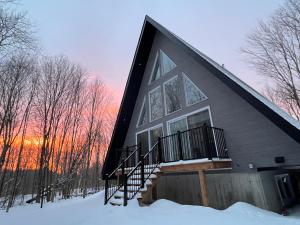 a house with a gambrel roof in the snow at Kartalla - the A frame experience in Tremblant in Saint-Rémi-dʼAmherst