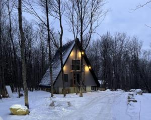 una piccola casa nella neve con le luci accese di Kartalla - the A frame experience in Tremblant a Saint-Rémi-dʼAmherst