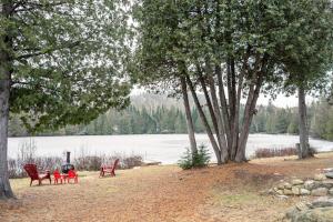 a group of chairs sitting next to a fire next to a lake at Casa Olej Unforgettable getaway in Tremblant & SPA in Saint-Rémi-dʼAmherst