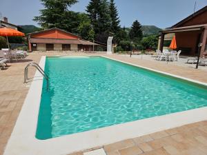 a large swimming pool with blue water at Agriturismo Ca Serrantonio - Ferri Appartamento Puccini in Urbania