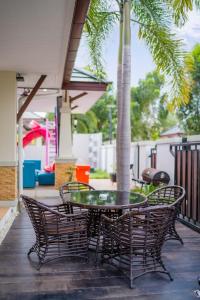 un patio con sedie, tavolo e palma di Barbie Pool Villa Na Jomtien a Na Jomtien