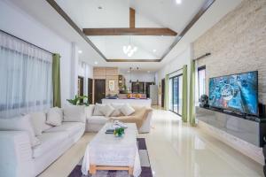 un soggiorno con mobili bianchi e TV a schermo piatto di Barbie Pool Villa Na Jomtien a Na Jomtien