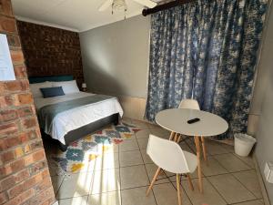 a bedroom with a bed and a table and chairs at Tranquilo Guesthouse in Ermelo