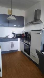 a kitchen with black and white appliances and wooden floors at Doppelzimmer Erfurt in Erfurt