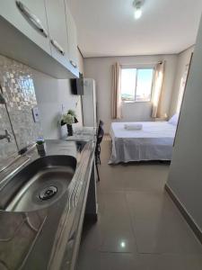 a bathroom with a sink and a bed in a room at Kitnet303 centro, c linda vista janela, tv smart in Montes Claros