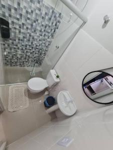 a white bathroom with a toilet and a mirror at Kitnet303 centro, c linda vista janela, tv smart in Montes Claros +12 photos