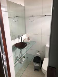 a bathroom with a glass sink and a toilet at Cantinho do Abaís, Condominio Meridiem Praia Mar in Praia Da Caueira